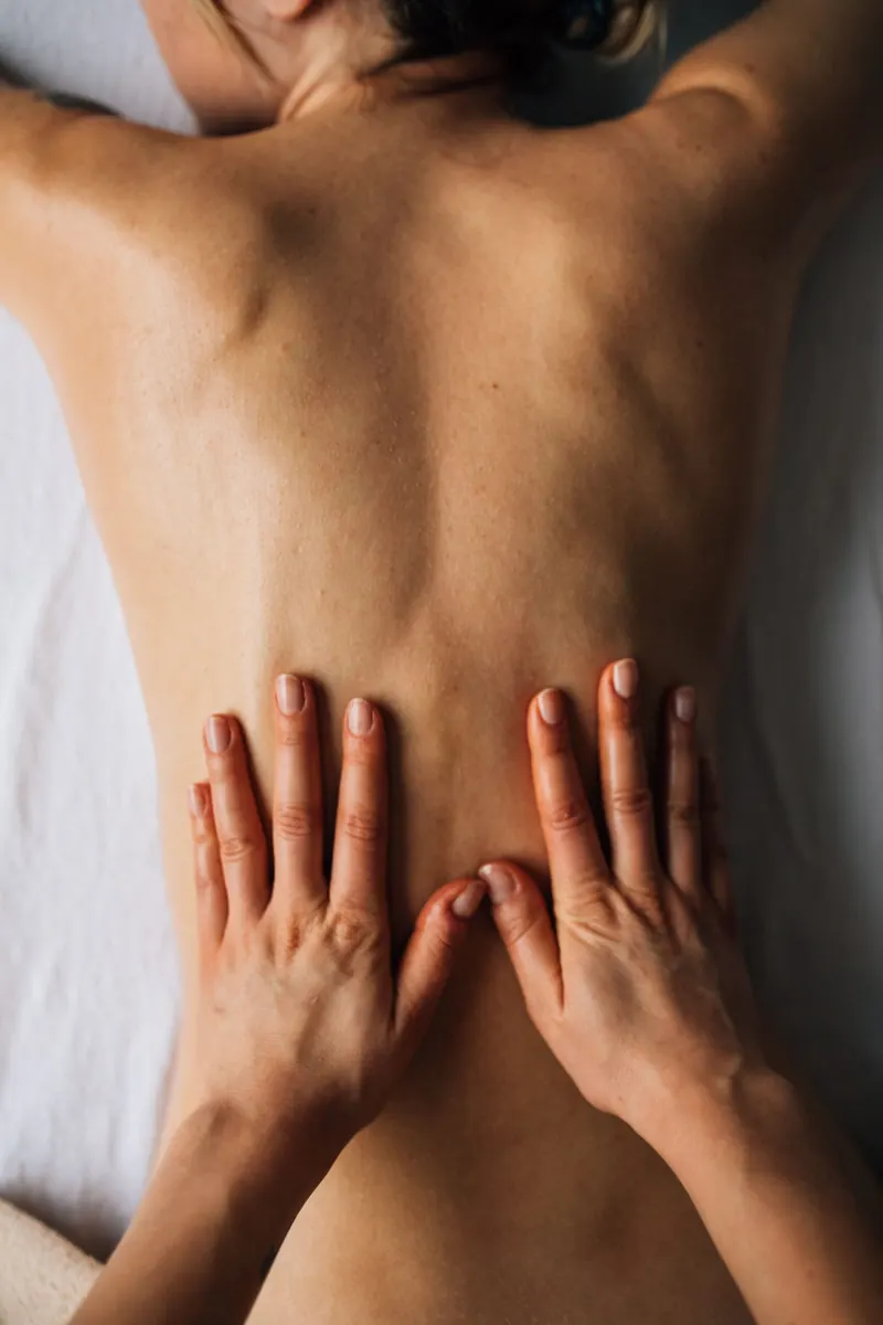 A therapist's hands on a client's lower back