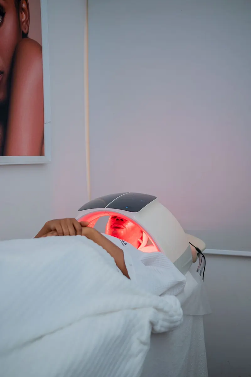 A client relaxing under an LED light therapy dome
